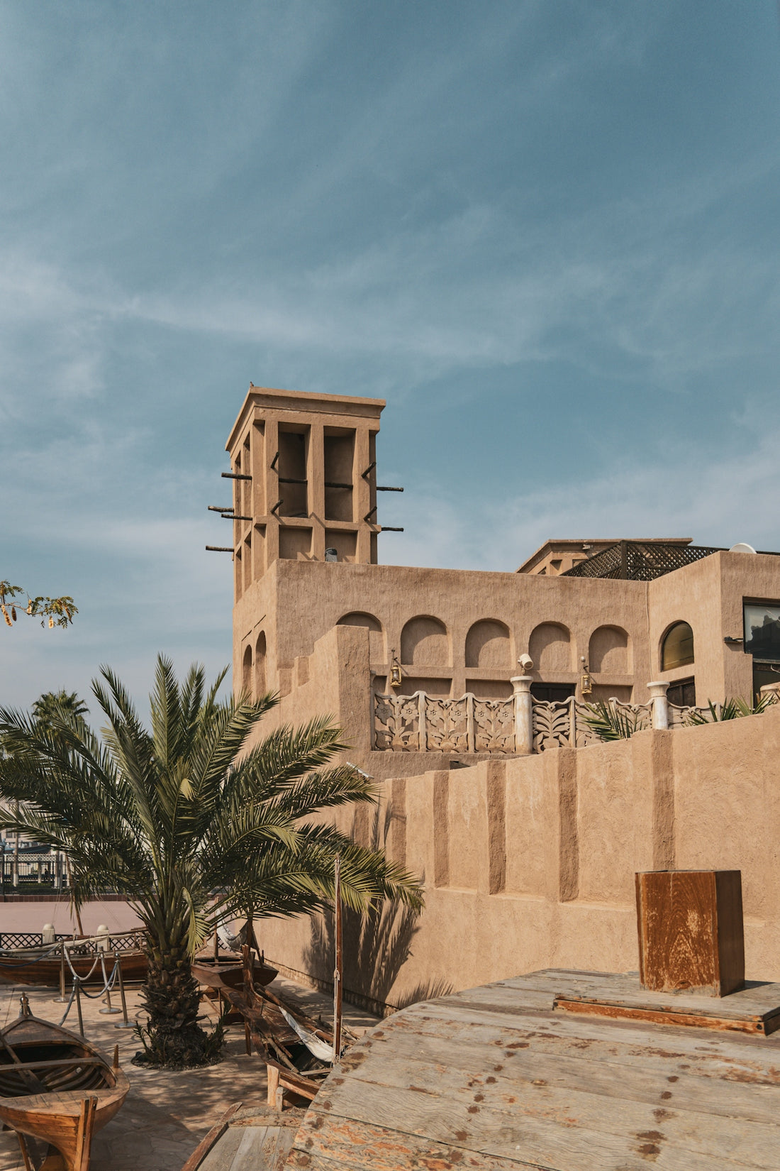 a brown building with a clock tower next to a palm tree