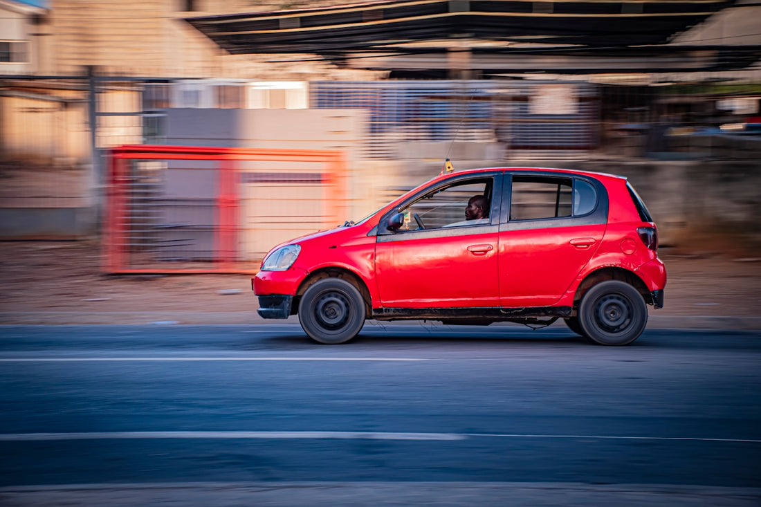 A red car driving on a road with motion blur